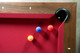 Overhead corner view of Doc & Holliday Billiards Santorini Slate Pool Table showing walnut rail with mother of pearl billiard sites, red Championship felt, and luxury billiard balls Overhead corner view of Doc & Holliday Billiards Santorini Slate Pool Table showing walnut rail with mother of pearl billiard sites, red Championship felt, and luxury billiard balls